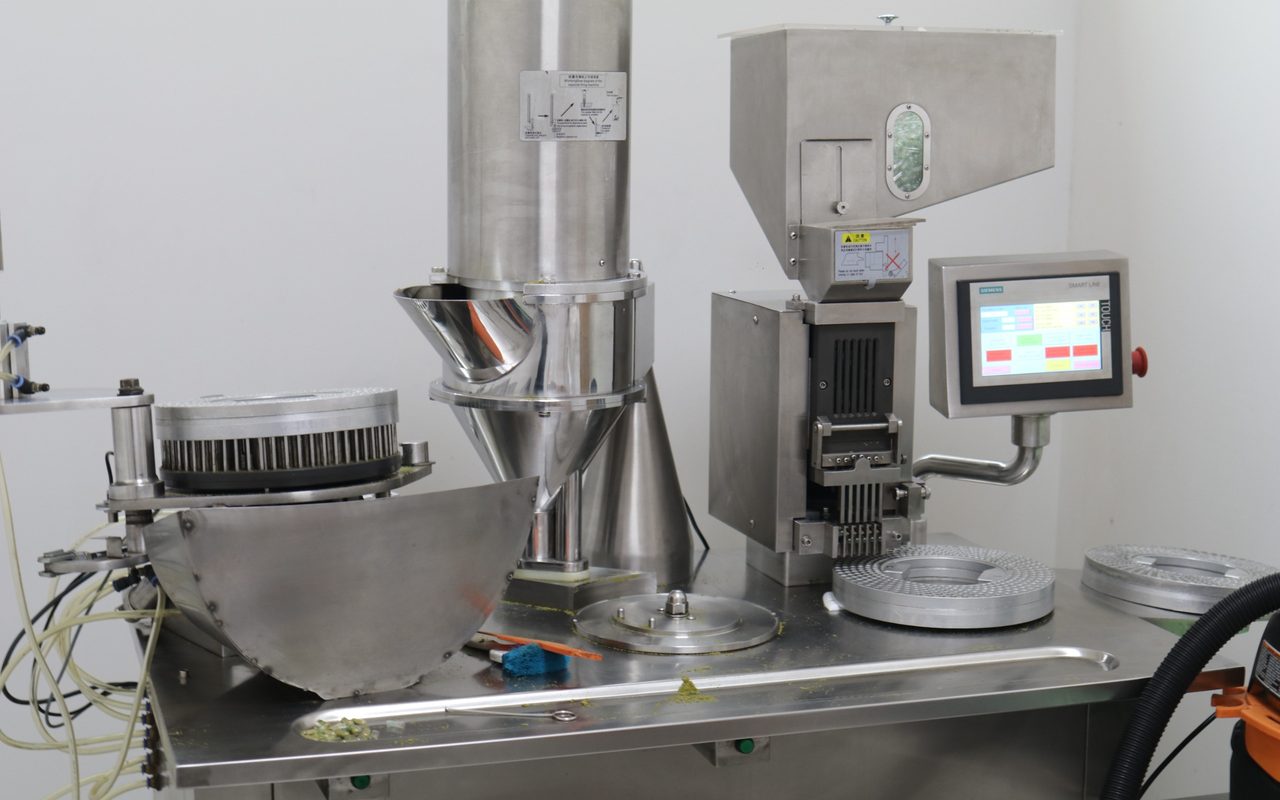 Encapsuladora de Laboratorios PHN en la sala de producción, con la tolva de alimentación, el cabezal dosificador y el panel de control.